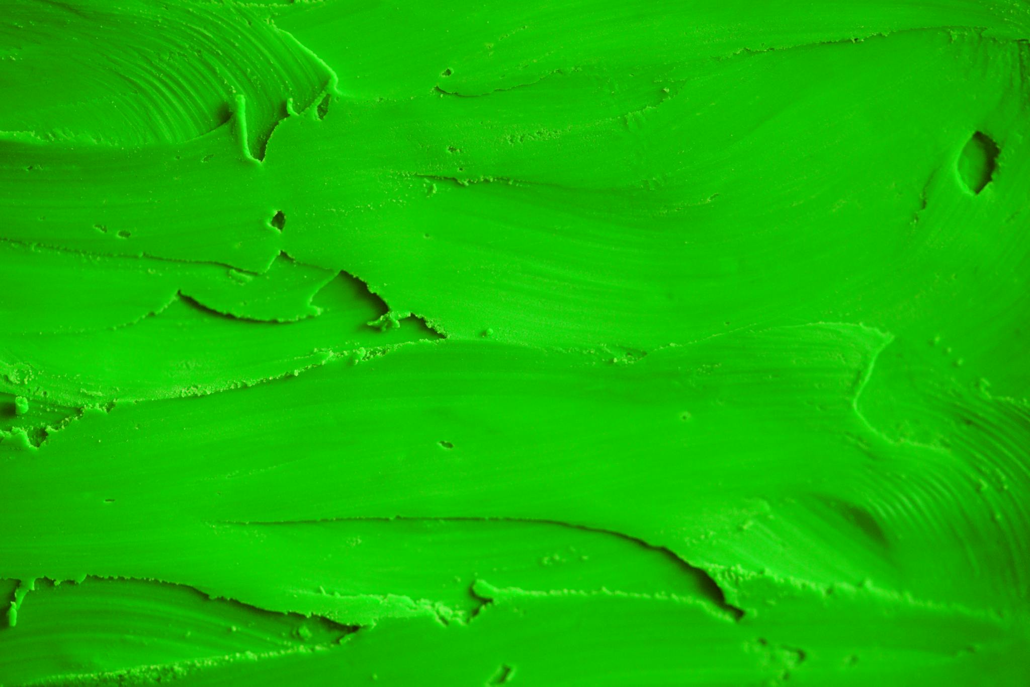 Close-up of a vibrant green textured surface with brush strokes, ideal for backgrounds and design.